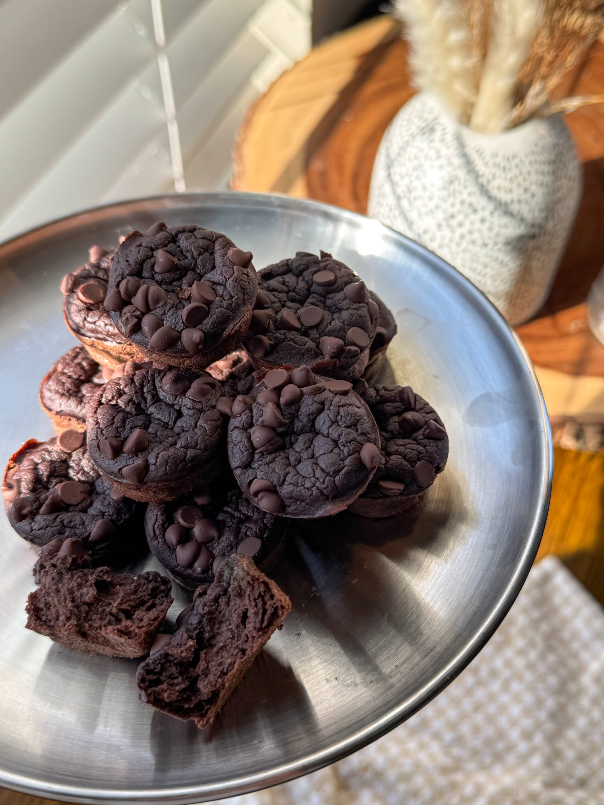 close-up of fudgy black bean brownie bites stacked on a stainless steel plate, showing moist texture
