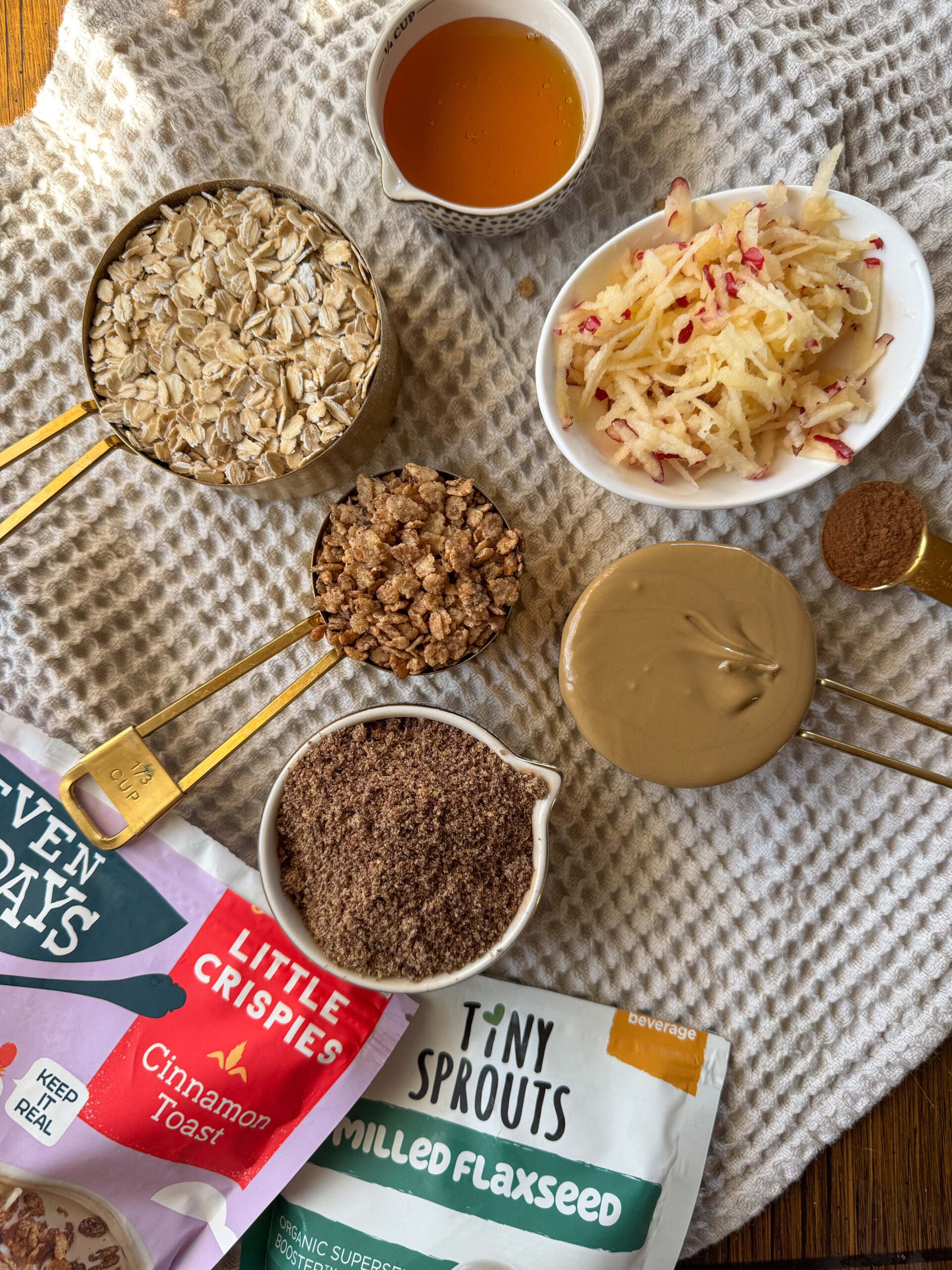 shredded apple, rolled oats, nut butter, ground flaxseed, honey, and cinnamon laying on the table
