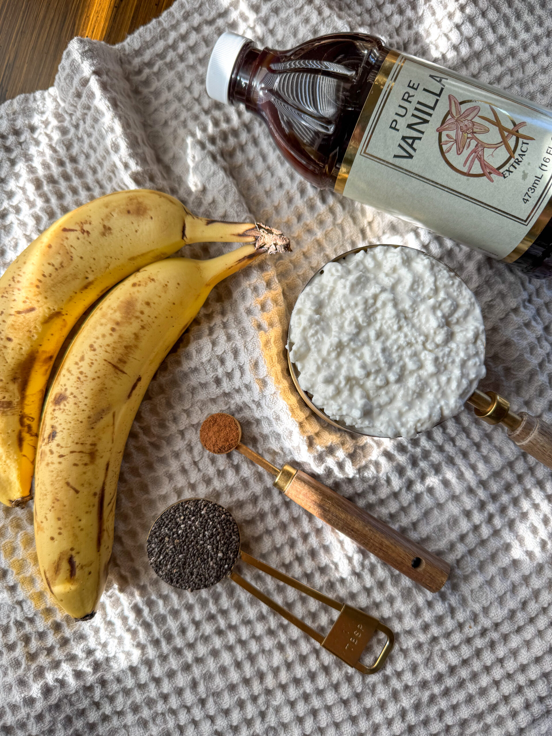 bananas, vanilla extract, cottage cheese, chia seeds, cinnamon on a table