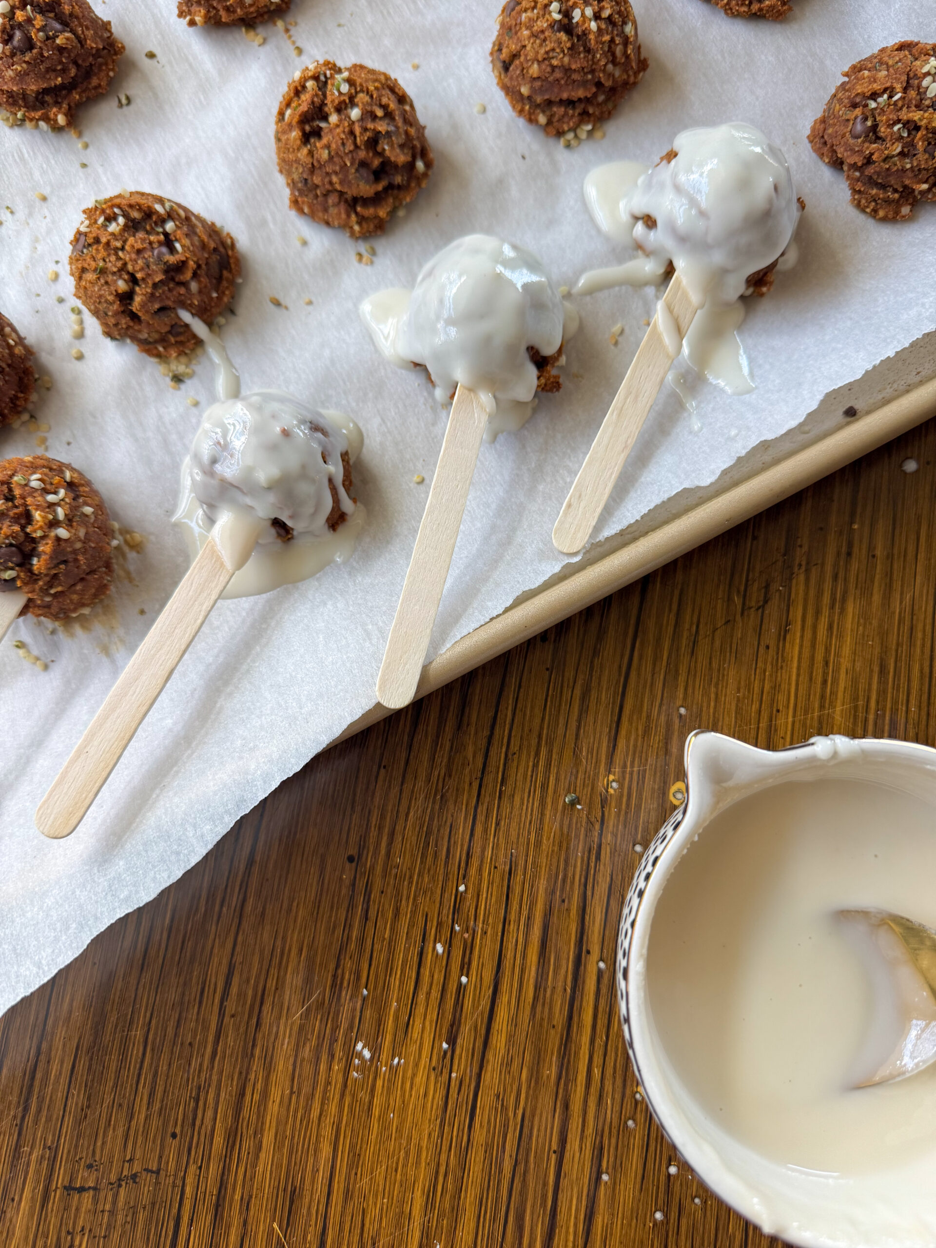 cake pops being iced on baking sheet