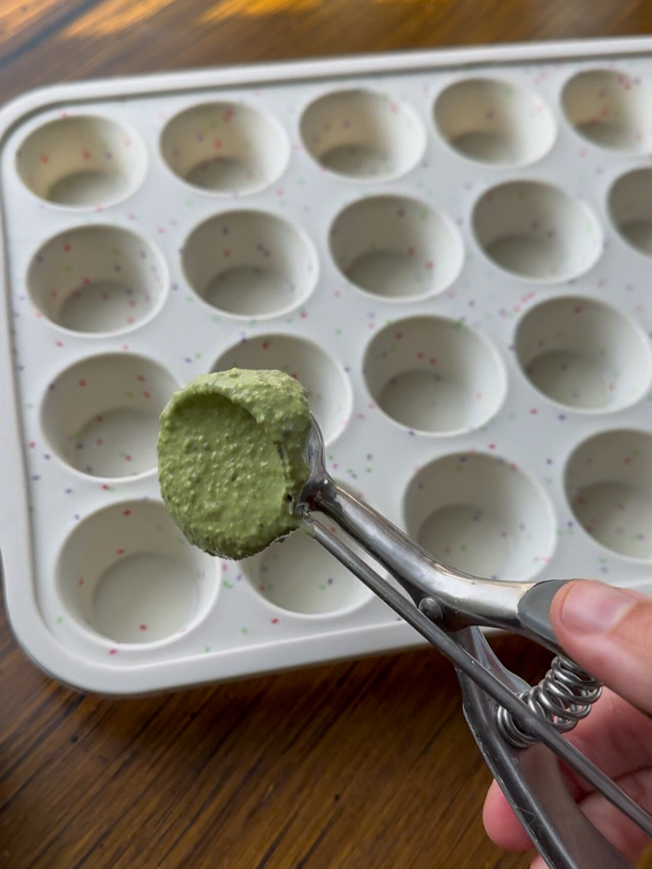 adding the spinach oatmeal batter into the muffin tin