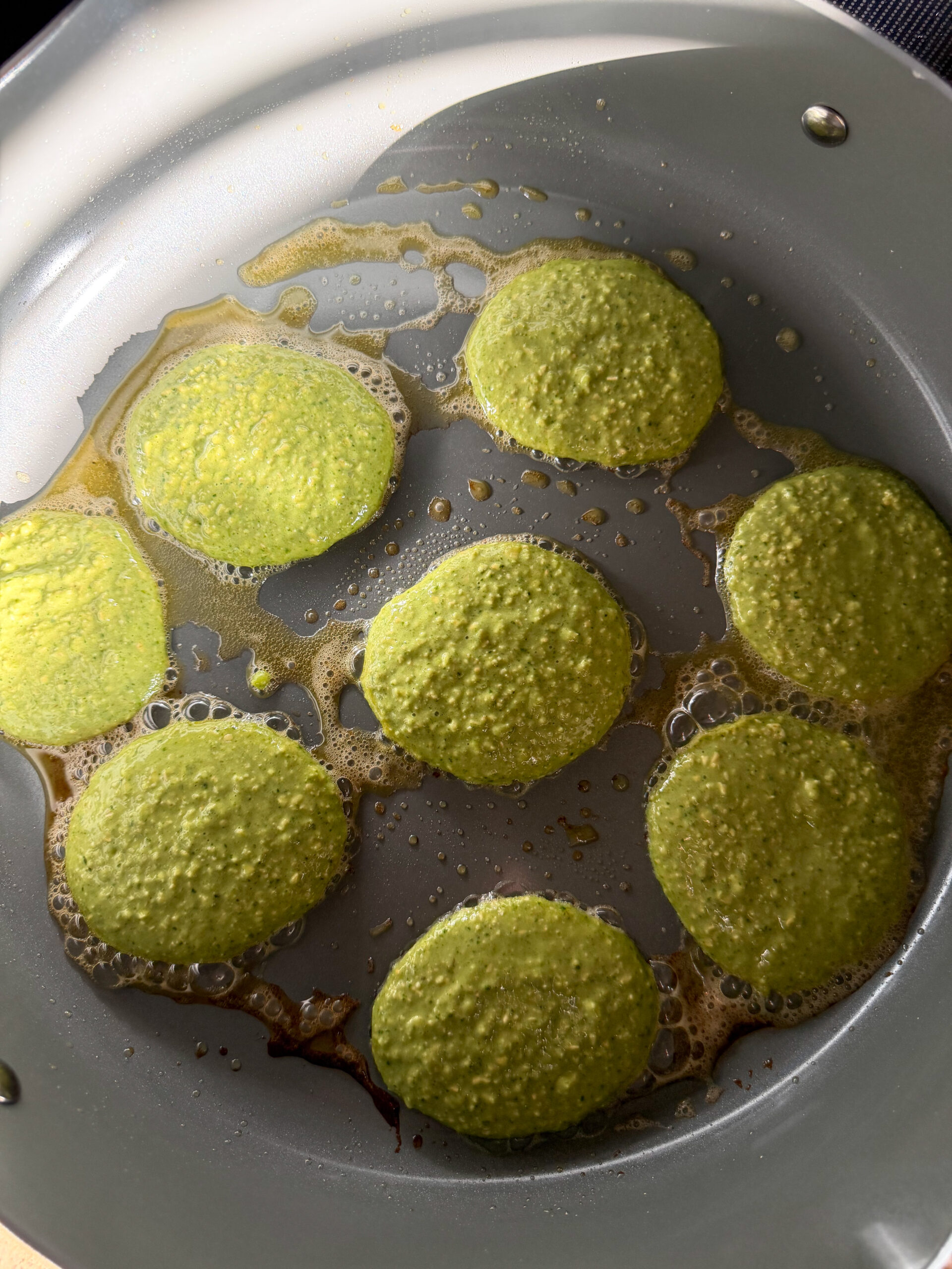 cooking spinach banana pancakes on a skillet