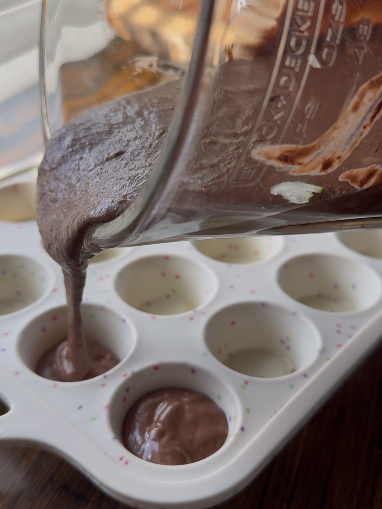 pouring the brownie dough in the mini muffin pan