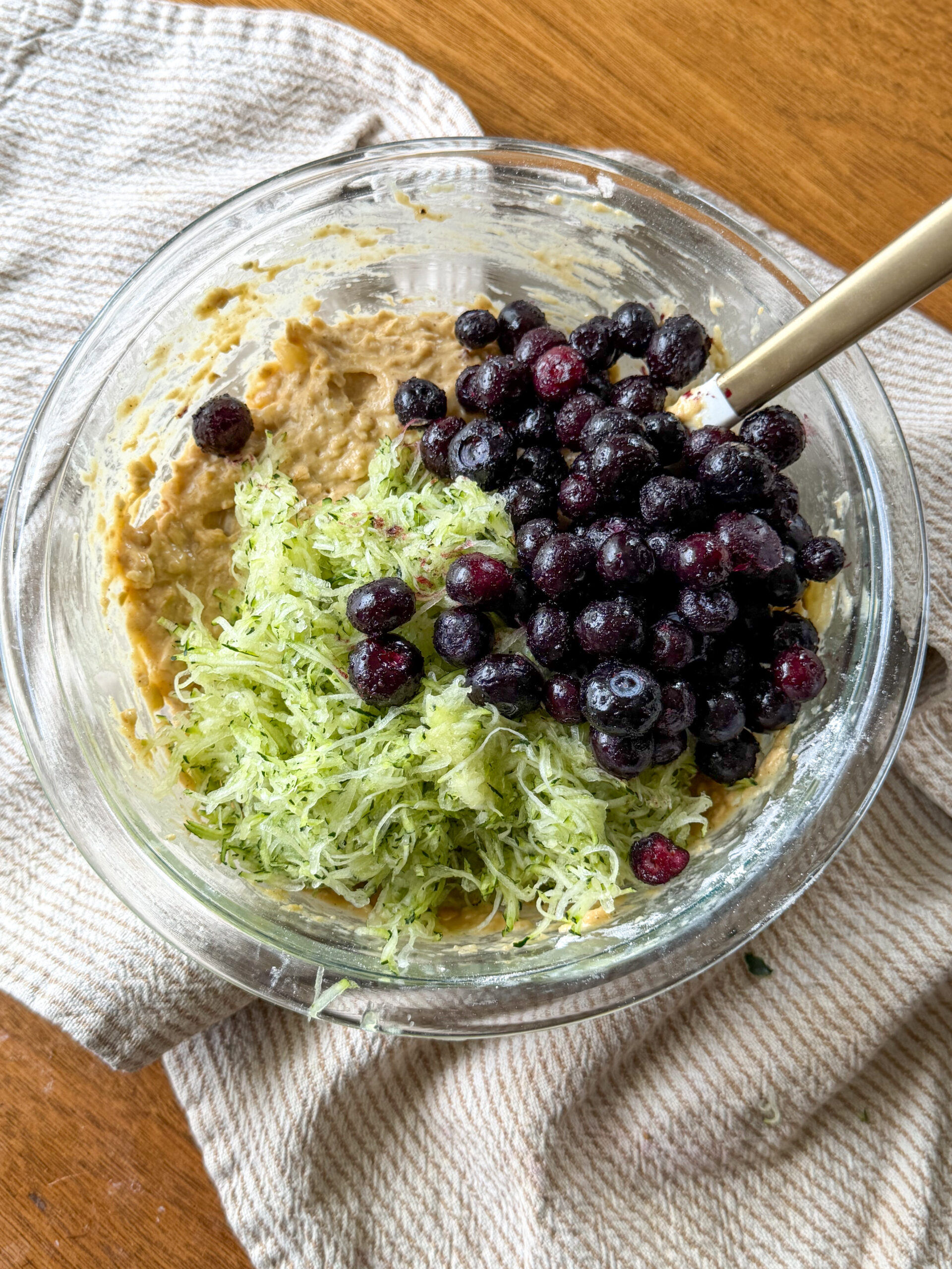 mixing the banana zucchini muffin batter with blueberries